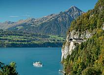 Märchenhafte Kulisse: Blick von Sundlauenen seeabwärts zum Niesen und zur Verbindungsstrasse am rechten Seeufer sowie auf den Thunersee mit dem Kursschiff der BLS. (bei Klick vergrösserte Ansicht Bild)